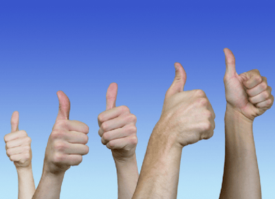 Several human hands giving thumbs up gesture against a clear blue sky background, expressing positivity and approval.