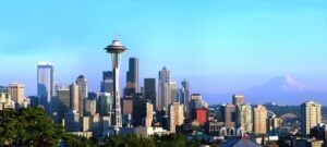 Downtown Seattle skyline featuring the Space Needle and modern skyscrapers under blue sky with Mount Rainier visible in the distance.