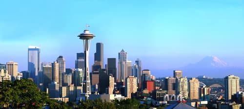Downtown Seattle skyline featuring the Space Needle and modern skyscrapers under blue sky with Mount Rainier visible in the distance.