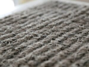 Close-up macro view of an air conditioning filter showing the woven fibers and textured surface pattern in gray and white tones.