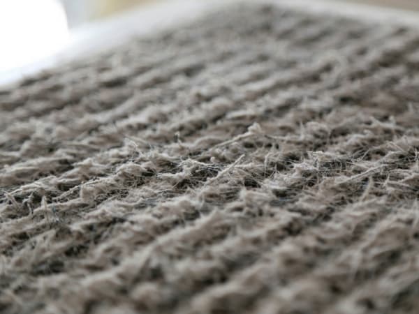 Close-up macro view of an air conditioning filter showing the woven fibers and textured surface pattern in gray and white tones.