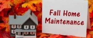 A model house with a white card reading 'Fall Home Maintenance' displayed against colorful autumn leaves.