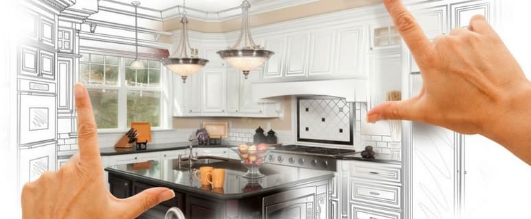 Hands framing a modern kitchen design sketch showing white cabinetry, black countertops, stainless steel appliances, and pendant lighting.