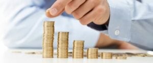 Person stacking gold coins in descending height order, representing financial growth, savings, and wealth management.