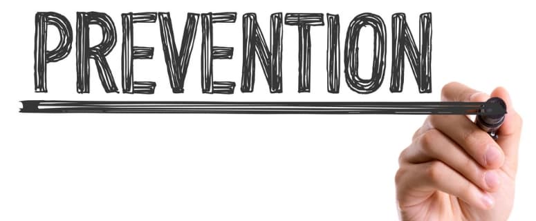 Hand holding a black marker drawing an underline beneath the word PREVENTION written in sketch-style lettering.