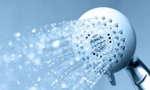 White circular shower head spraying water droplets against a blue background with bokeh lighting effects.