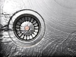 Close-up overhead view of a stainless steel garbage disposal drain with metal grinding chamber visible from above.
