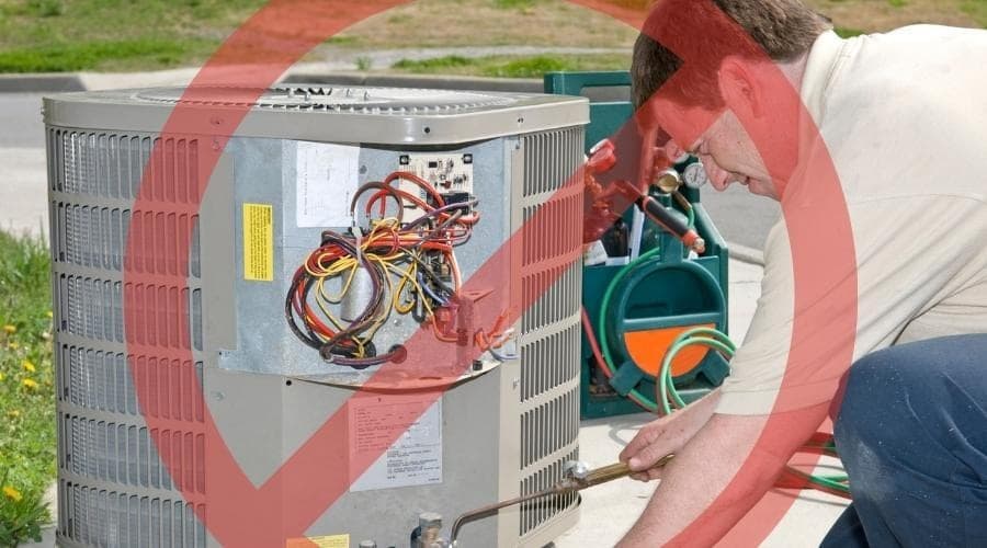 Man leaned over AC unit with a torch in his hand