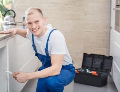 professional plumber kneeling by a counter